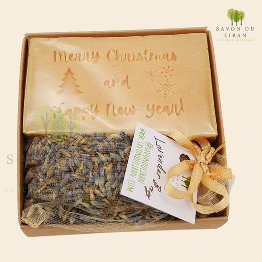 Christmas Serenity Handy Box with musk natural soap engraved with "Merry Christmas & Happy New Year" and lavender sachet, all in a 8x8x2.5 cm kraft box with transparent lid.