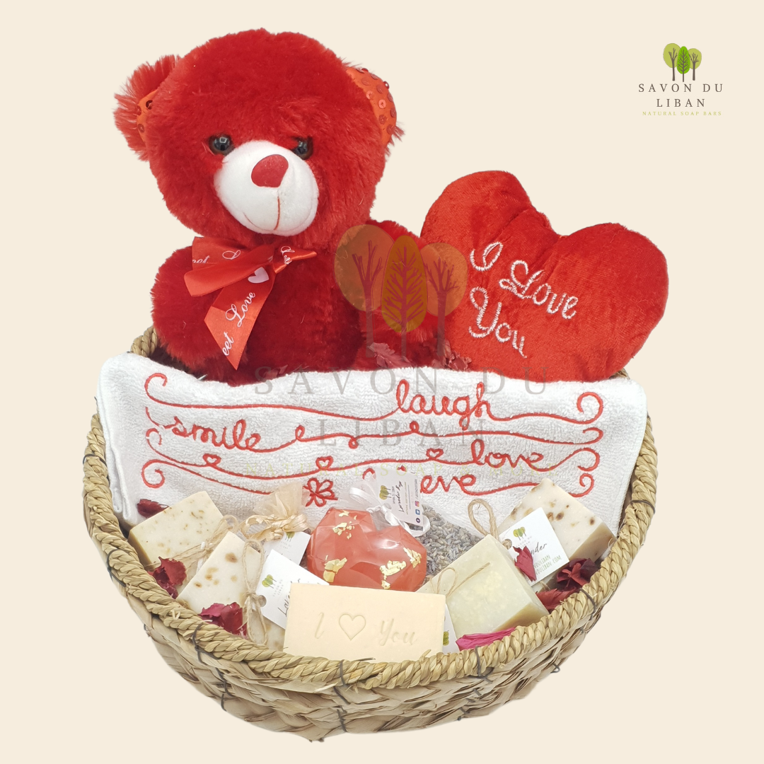 Cupid's Basket Gift Set featuring a red teddy bear, heart-shaped cushion, embroidered towel, and natural handmade soaps.