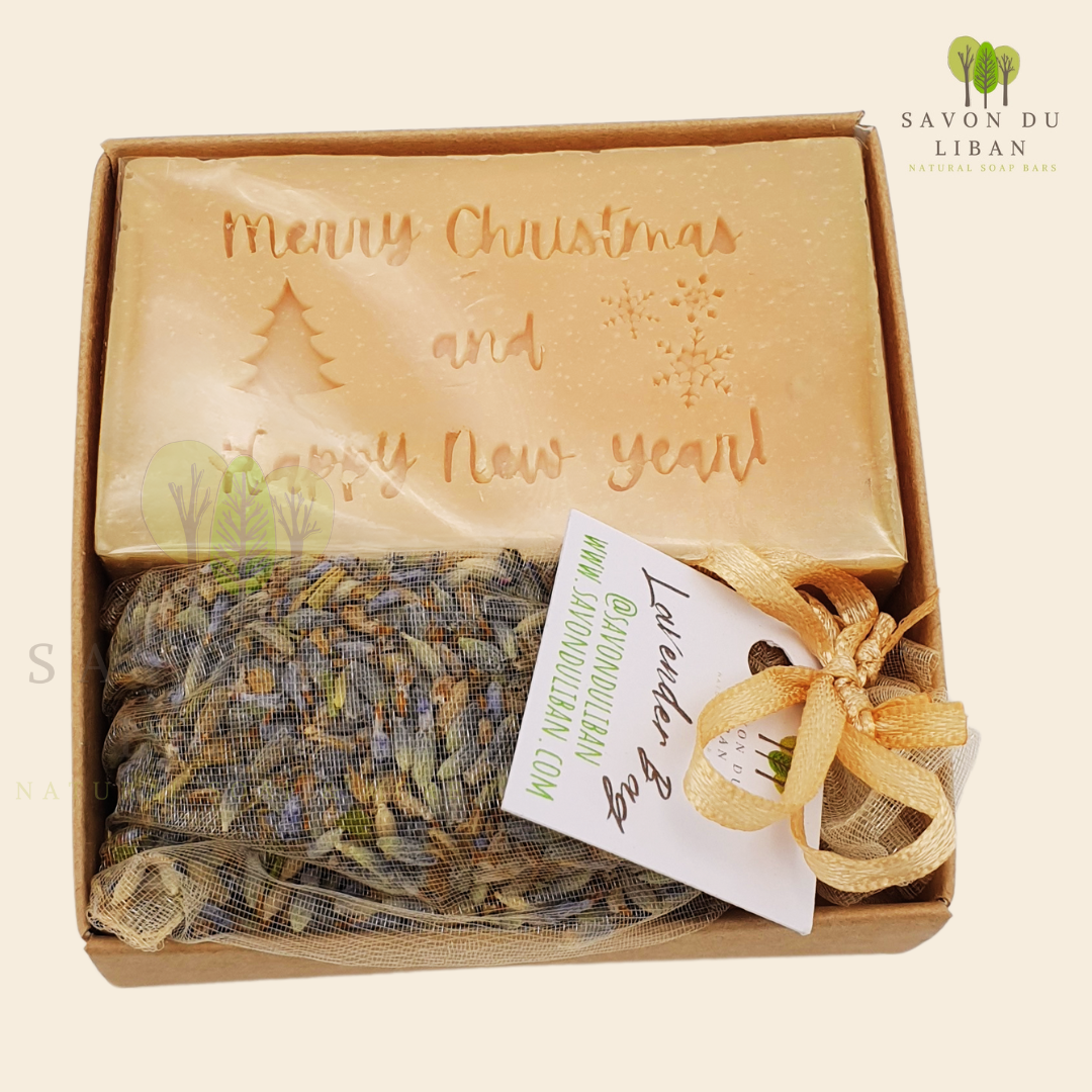 Christmas Serenity Handy Box with musk natural soap engraved with "Merry Christmas & Happy New Year" and lavender sachet, all in a 8x8x2.5 cm kraft box with transparent lid.