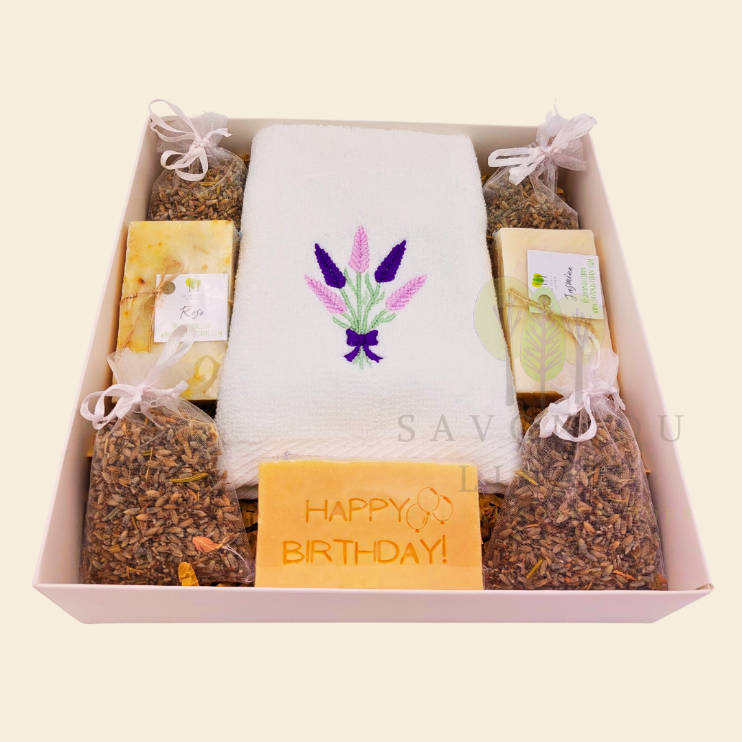 Lavender Moments birthday gift box with lavender towel, soaps, musk engraved bar, and lavender bags in a white box with transparent lid.