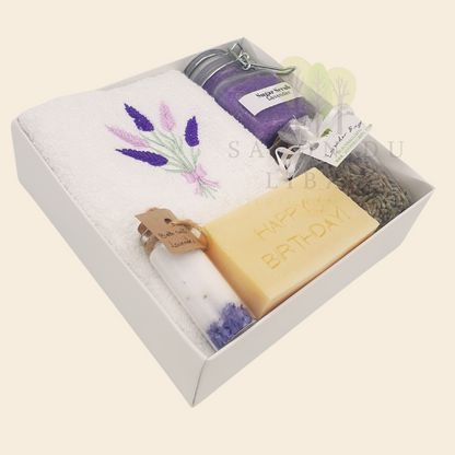 Whispers of Celebration spa set in white box: Sugar Scrub, Bath Salt, Lavender Buds, White Towel with Lavender Embroidery, Musk Soap stamped Happy Birthday