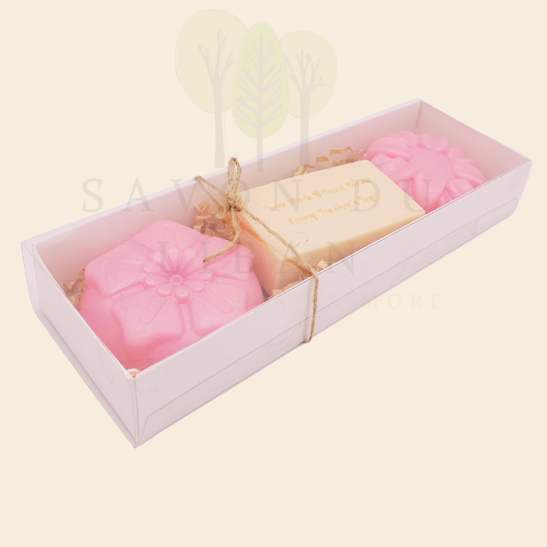 A Teacher’s Scent-sational Petals – The 2025 Teacher's Day Floral Gift Set with a Musk soap stamped 'Grow Minds ❤️ Touch Hearts - Happy Teacher's Day!' and two scented flower-shaped soaps in an elegant 23x8x3.5 cm box with transparent cover.