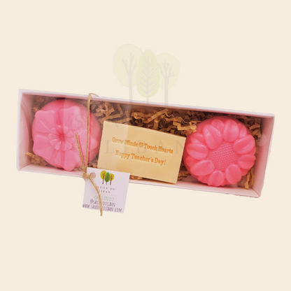 A Teacher’s Scent-sational Petals – The 2025 Teacher's Day Floral Gift Set with a Musk soap stamped 'Grow Minds ❤️ Touch Hearts - Happy Teacher's Day!' and two scented flower-shaped soaps in an elegant 23x8x3.5 cm box with transparent cover.